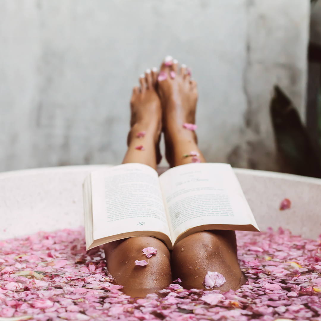 legs poking out of bath filled with petals